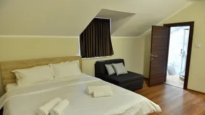 a bedroom with a large white bed and a chair at Apartmani Mali vikend in Belgrade