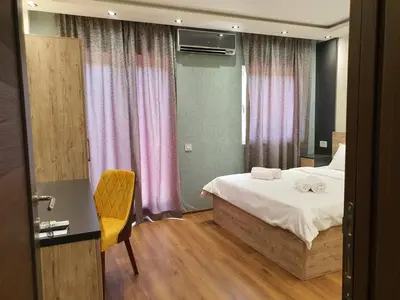 a hotel room with a bed and a desk and curtains at Apartmani Mali vikend in Belgrade