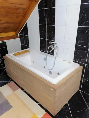 a bath tub in a bathroom with black tiles at Kućerak X in Ruma