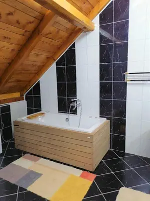 a bath tub in a room with black tiles at Kućerak X in Ruma