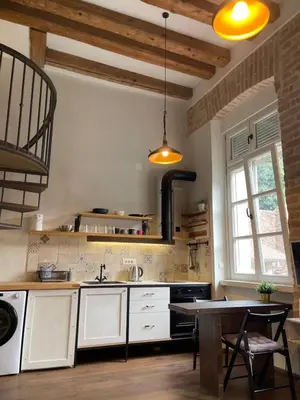a kitchen with white cabinets and a table in it at Old Port Riverside Apartments in City Center in Belgrade