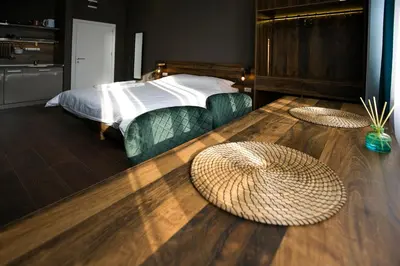 a bedroom with a bed with green chairs and wooden floors at East & West Apartments in Belgrade