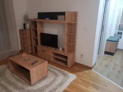 a living room with a television and a wooden entertainment center at Relax, apartman sa garažnim mestom in Obrenovac