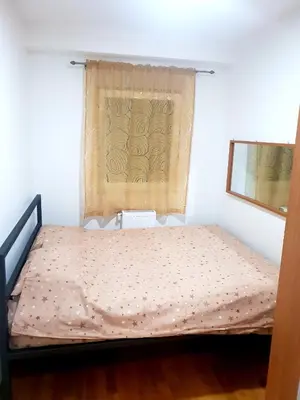 a bed in a room with a window with a curtain at Relax, apartman sa garažnim mestom in Obrenovac