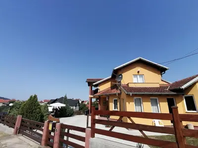 a yellow house with a wooden fence at Apartman Panorama Arandjelovac in Arandjelovac