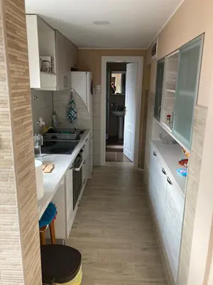 a small kitchen with white appliances and a hallway at House Apartment in Pančevo