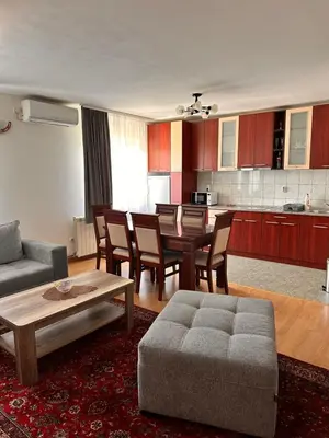 a living room with a table and chairs and a kitchen at Helena apartment in Belgrade