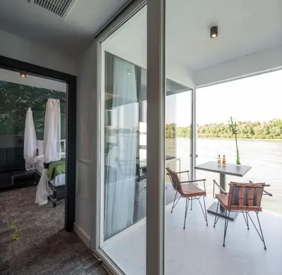 a room with glass doors and a table and chairs at Joy 5 Hotel & SPA in Belgrade