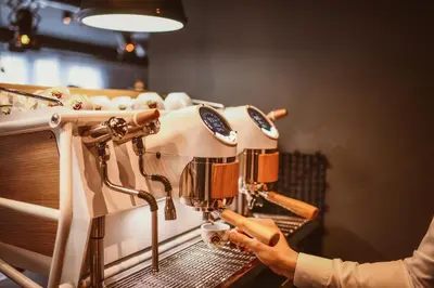 a person using a coffee machine in a coffee shop at Joy 5 Hotel & SPA in Belgrade