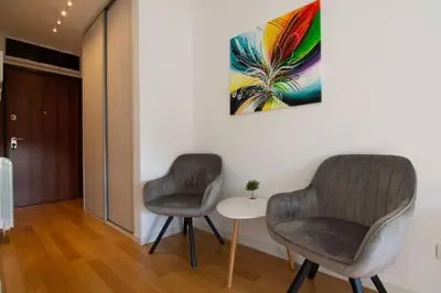 two chairs in a room with a table and a painting at A Blok New Modern - Free garage parking, comfortable, quiet with a park view in Belgrade