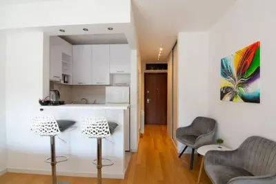 a living room with two chairs and a kitchen at A Blok New Modern - Free garage parking, comfortable, quiet with a park view in Belgrade