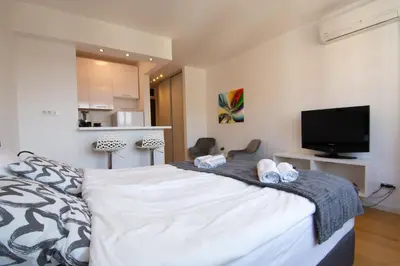a bedroom with a bed with a tv and shoes on it at A Blok New Modern - Free garage parking, comfortable, quiet with a park view in Belgrade