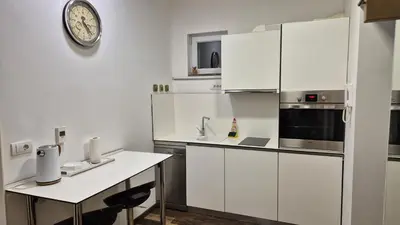 a kitchen with white cabinets and a clock on the wall at Cozy apartment in the center of Belgrade - living room, bedroom and bathroom in Belgrade
