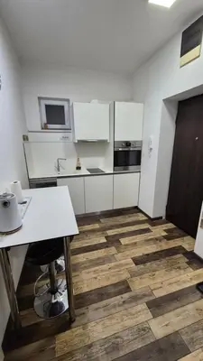 a kitchen with white cabinets and a wooden floor at Cozy apartment in the center of Belgrade - living room, bedroom and bathroom in Belgrade