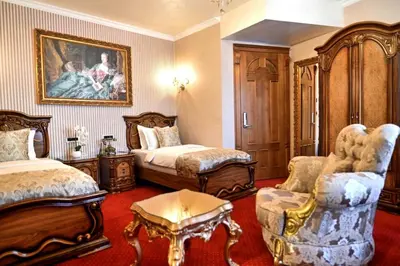 a bedroom with two beds and a table and chairs at Prezident Palace Belgrade - Luxury Boutique Hotel & Spa in Belgrade