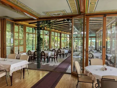 a restaurant with tables and chairs and glass walls at Vila club 011 in Dedinje