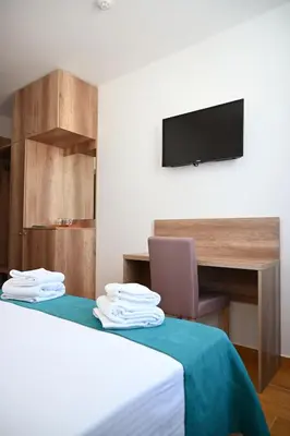 a room with a bed with a desk and a television at Dona, Altina in Belgrade