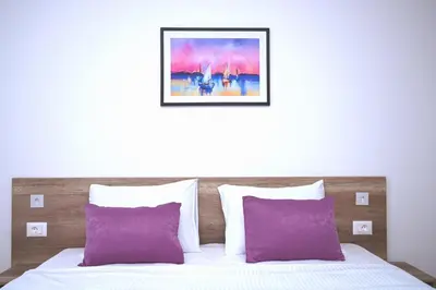 a bed with purple pillows and a picture above it at Dona, Altina in Belgrade