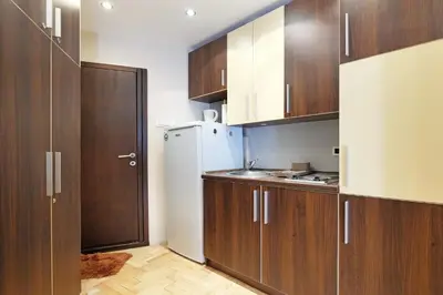 a kitchen with wooden cabinets and a white refrigerator at Studio Paradise Forest in Belgrade
