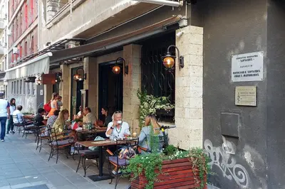 a group of people sitting at tables outside a restaurant at Studio Paradise Forest in Belgrade