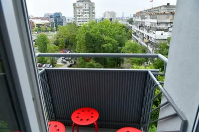 a balcony with red chairs and a view of a city at Apartment Vanilla Belgrade in Belgrade