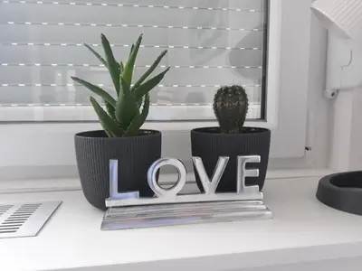 two plants sitting on a window sill with a love sign at Apartment Vanilla Belgrade in Belgrade