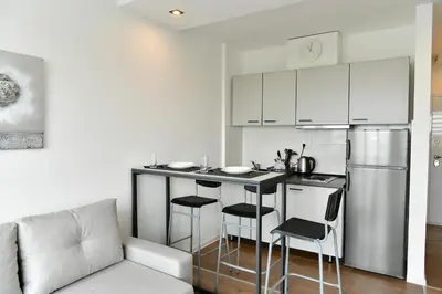 a kitchen with a bar with stools and a refrigerator at Apartment Vanilla Belgrade in Belgrade