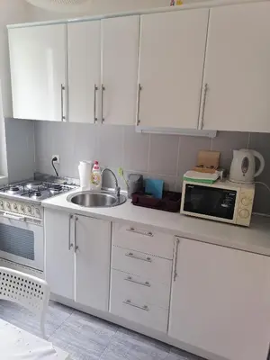 a kitchen with white cabinets and a sink and a microwave at Apartman Garden House in Voždovac