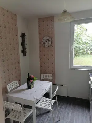 a dining room table with chairs and a clock on the wall at Apartman Garden House in Voždovac