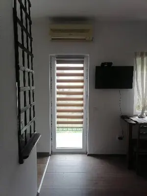 a room with a door and a window with blinds at Apartman Garden House in Voždovac
