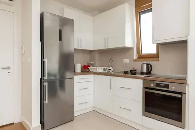 a kitchen with a stainless steel refrigerator and white cabinets at Zemun Luxury - Comfortable, workspace, quiet, free parking, Netflix in Belgrade