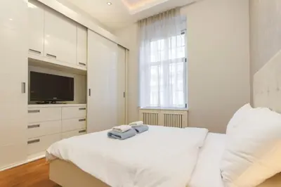 a white bedroom with a bed and a television at Central Park Residence in Belgrade