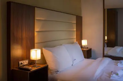 a bedroom with a bed with white pillows and two lamps at Central Park Residence in Belgrade