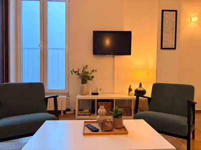 a living room with two chairs and a table and a tv at City Break Apartments Chic and Luxury in Belgrade