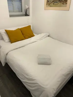 a bed with white sheets and yellow pillows at Bibi's apartment in Belgrade