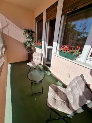 a balcony with two chairs and a table and a window at Large, Spacious Apartment Voždovac in Belgrade