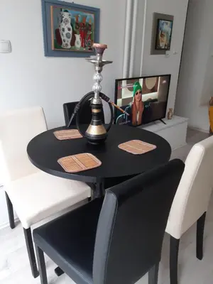 a black dining room table and chairs with a girl on the tv at Djakuzi Viktorija in Belgrade