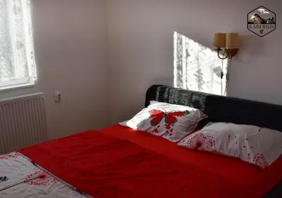 a bed with a red blanket and two pillows on it at Baberius in Babe