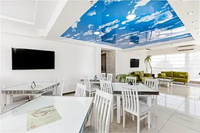 a dining room with white tables and chairs and a flat screen tv at ForS Konak Apartments in Belgrade