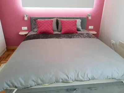 a bedroom with a large bed with pink walls at Kalemegra in Belgrade