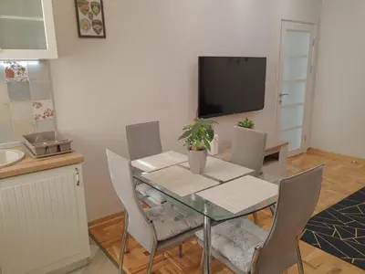 a dining room with a table with chairs and a tv at Kalemegra in Belgrade