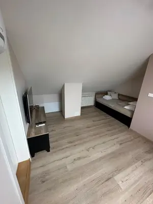 an attic room with a bed and a television at Apartments LaVu in Belgrade