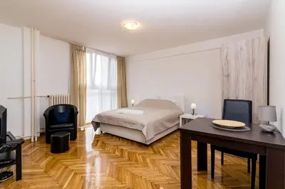 a bedroom with a bed and a desk and a table at Apartman Pionir in Belgrade