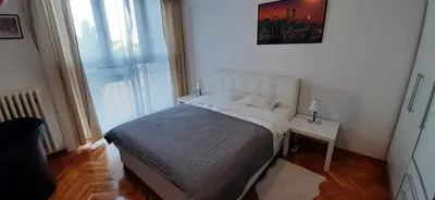 a small bedroom with a bed and a window at Apartman Pionir in Belgrade