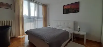 a bedroom with a bed and a large window at Apartman Pionir in Belgrade