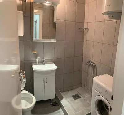 a bathroom with a toilet and a sink and a washing machine at Apartman Pionir in Belgrade