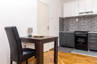 a kitchen with a wooden table and a black chair at Apartman Pionir in Belgrade