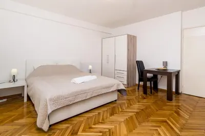 a white bedroom with a bed and a desk at Apartman Pionir in Belgrade