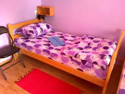 a bed with a purple comforter with a laptop on it at Hostel M in Belgrade