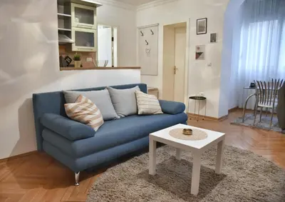 a blue couch in a living room with a table at Apartment Carpe diem in Belgrade in Belgrade